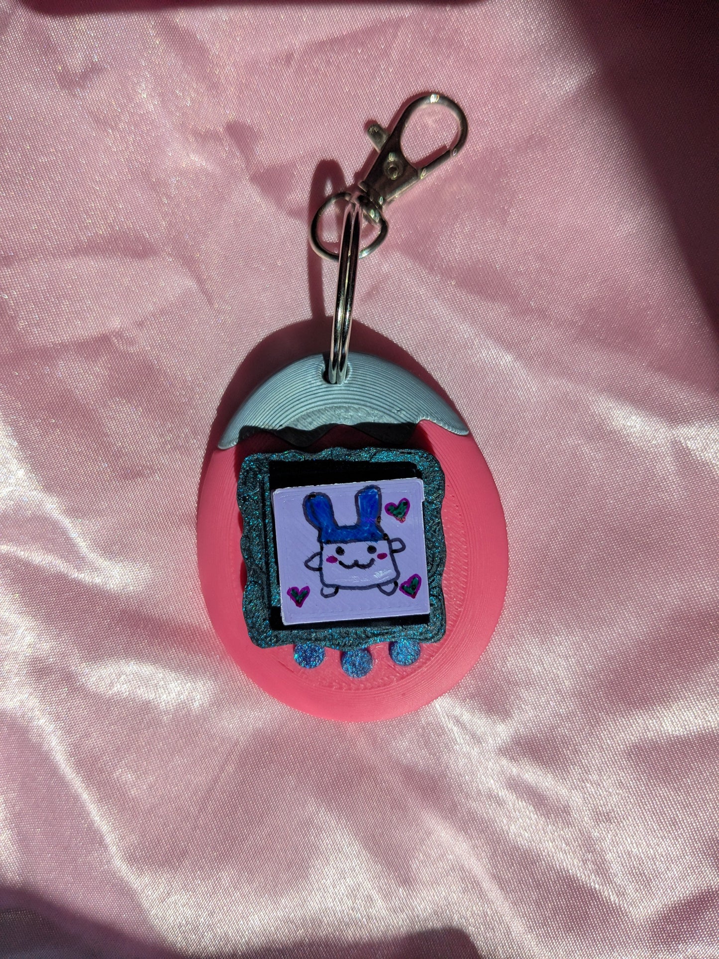 Keychain with cartoon character design on a pink fabric background