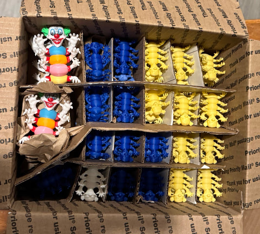Box of small toy figures in various colors packed safely inside a cardboard box.