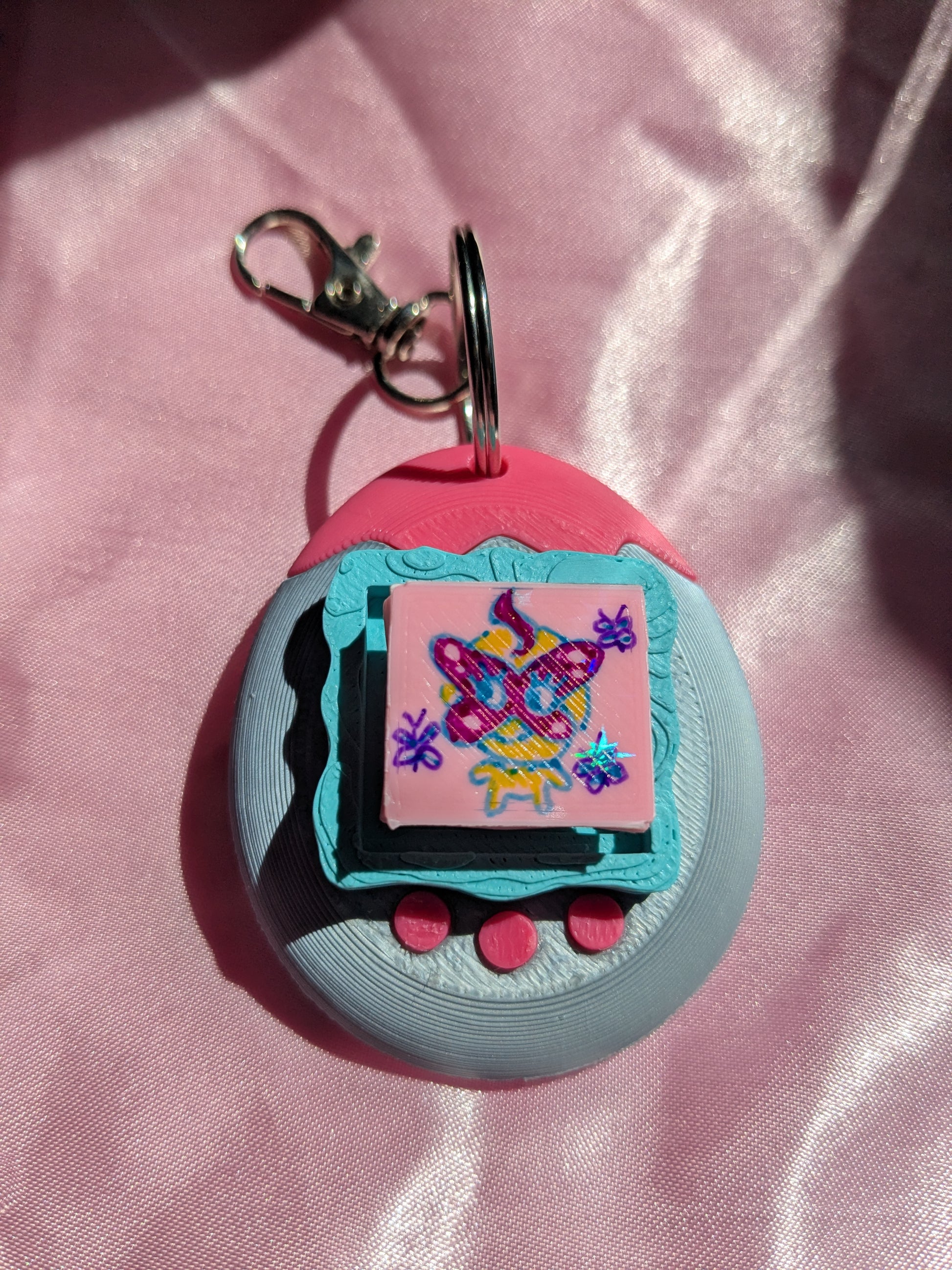 Keychain with colorful design on a pink fabric background