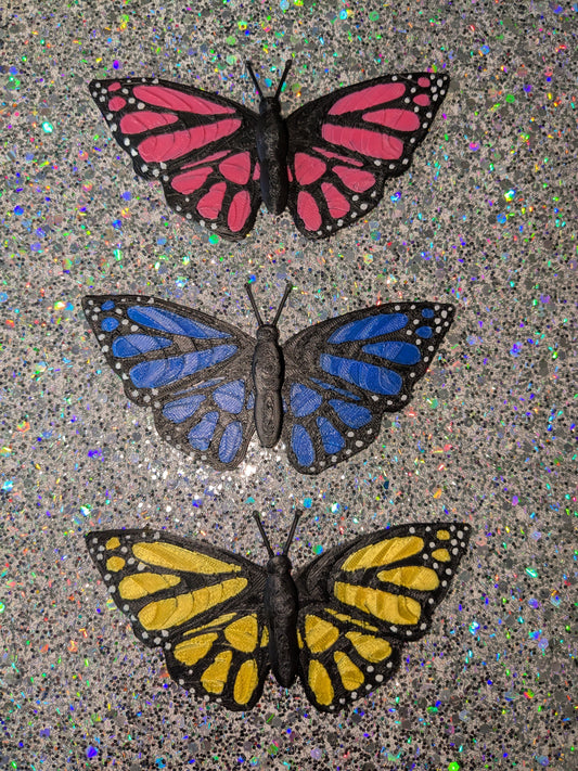 Three butterflies with red, blue, and yellow wings on a glittery background